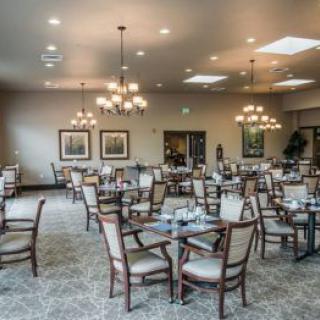 An empty dining room with multiple tables and chairs, elegantly decorated with chandeliers.