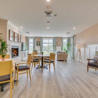 A spacious and modern living room with ample seating, large windows, and a cozy fireplace.