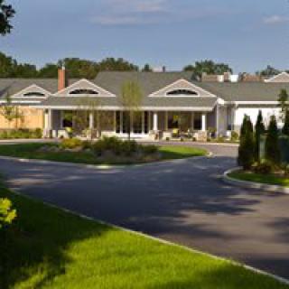 A residential building with a circular driveway surrounded by trees on a sunny day.