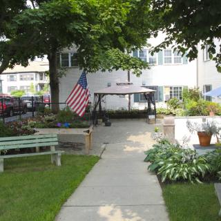 A peaceful outdoor garden with benches, a pathway, and an American flag.
