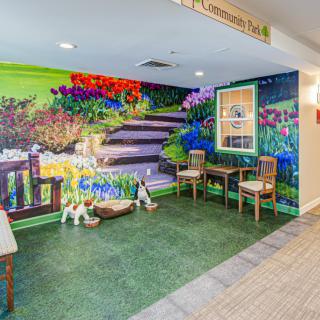 A vibrant indoor mural depicting a garden scene with seating area.