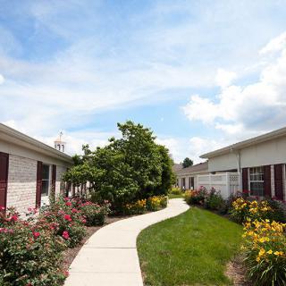 A scenic pathway flanked by gardens between two buildings, under a clear blue sky.