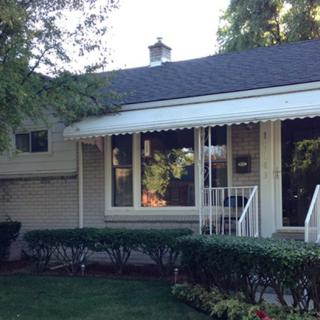 A quaint residential house with a well-kept front yard and an awning over the front window.