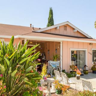 A charming house with a vibrant garden and cozy patio, perfect for enjoying a sunny day.
