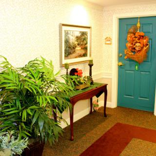 A cozy hallway featuring a decorative table, vibrant plant, and an inviting teal door.
