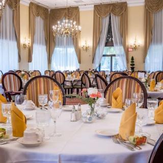 An elegant dining room with formal table settings and chandeliers.