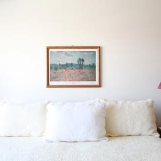 A cozy living room setup featuring a framed painting above a soft sofa.