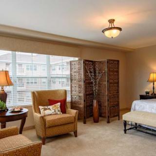 A cozy bedroom with stylish interior design featuring a comfortable chair, bedside lamps, and large windows.