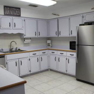 A modern kitchen with white cabinets, stainless steel appliances, and a tiled floor.