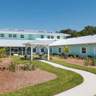 A modern residential building with a landscaped garden and pathway under a clear blue sky.