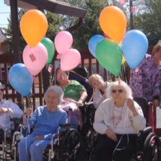 Residents enjoying a cheerful outdoor event with colorful balloons.