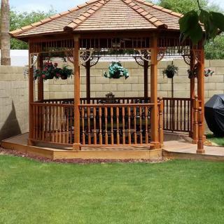 A wooden gazebo set in a lush green backyard, perfect for outdoor relaxation.