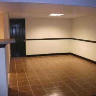 A vacant interior space featuring tiled flooring and a single door.