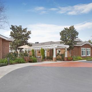 A scenic view of a brick building surrounded by greenery and a clear sky.