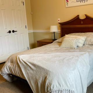 A cozy bedroom with a neatly made bed, side table, and lamp.