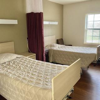 A shared hospital room with two patient beds separated by a privacy curtain.