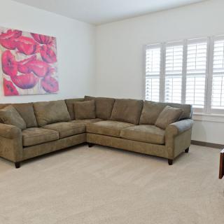 A cozy living room with a corner sofa and colorful wall art.