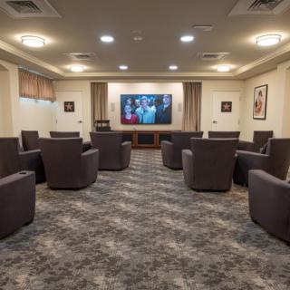 A modern home theater room with comfortable seating and a large screen TV.