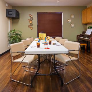 A cozy dining room setup with a table and six chairs, surrounded by indoor plants and decor.