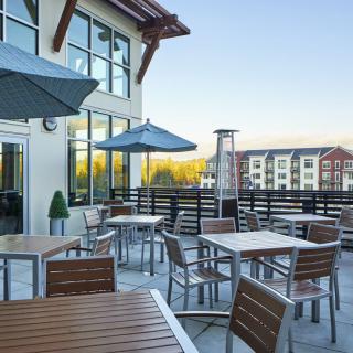 Rooftop patio with tables and umbrellas overlooking a residential area.