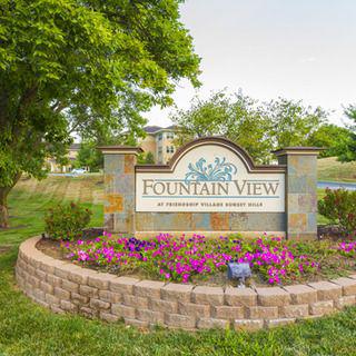 A landscaped entrance sign for Fountain View with colorful flowers and a stone wall.
