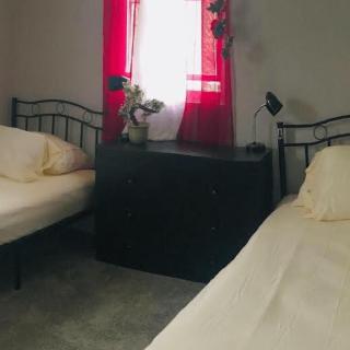A minimalist bedroom with two twin beds and a red curtain.