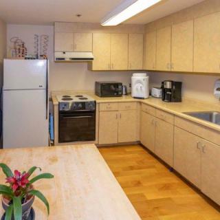 A modern kitchen with light wood cabinets and various appliances.