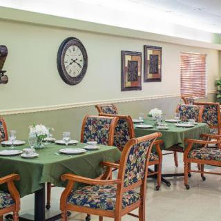 An elegant dining area with green tablecloths and floral patterned chairs.