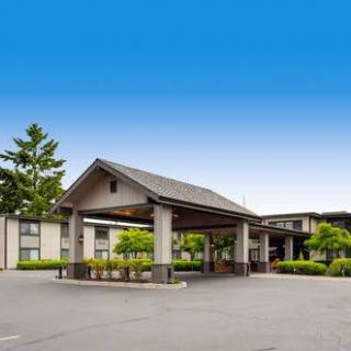 Exterior view of a hotel entrance with a covered canopy and parking area under a clear blue sky.