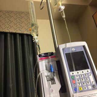 A hospital room showing an IV drip connected to a medical infusion pump.
