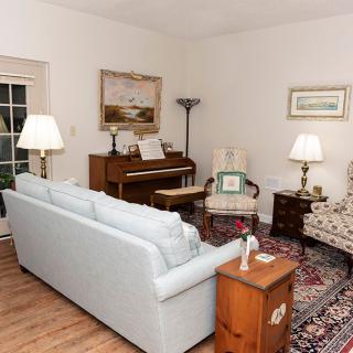 A cozy living room featuring a piano, comfortable seating, and decorative items.