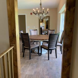 A cozy dining room featuring a round table with chairs, a chandelier overhead, and wooden flooring.