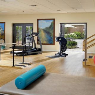 A well-equipped gym with exercise machines and a yoga mat in a bright, open space.