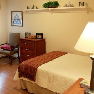 A cozy bedroom with a neatly made bed, wooden furniture, and soft lighting.