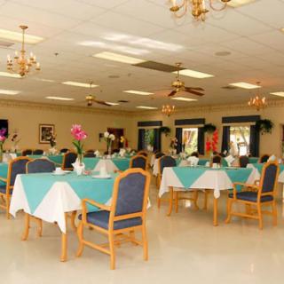 A spacious dining room with elegantly set tables and chairs, featuring warm lighting and decor.