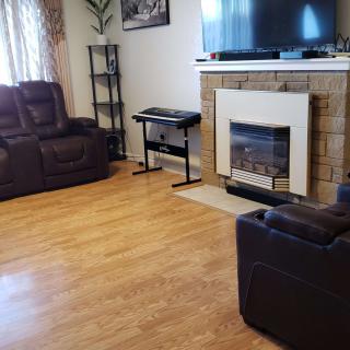 A modern living room featuring a sofa, fireplace, and TV with wood flooring.