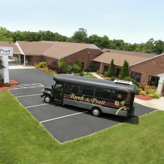 A black shuttle bus parked outside a brick building with a neatly maintained lawn.