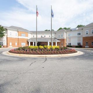 A large building with a circular driveway featuring landscaping and flags at the entrance.