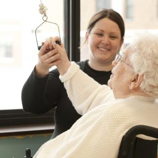 A caregiver assists an elderly person, providing support and care in a nursing home setting.