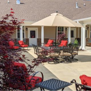A cozy outdoor patio featuring red-cushioned chairs, tables, and a large umbrella.