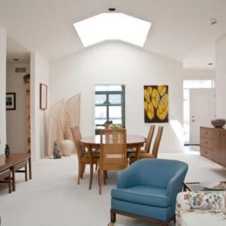 A bright and modern dining area with a skylight, featuring minimalist decor and contemporary furniture.