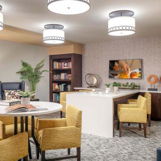 A modern living space featuring a dining area and bookshelf, with contemporary furniture and decor.