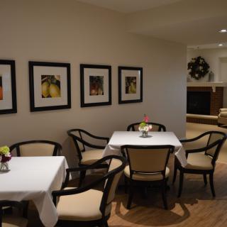 A cozy dining area featuring tables with white tablecloths and framed artwork on the walls.