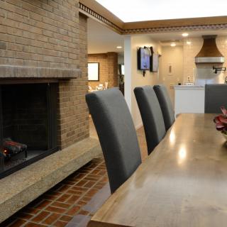 A modern interior featuring a dining area with a fireplace and an adjoining kitchen.