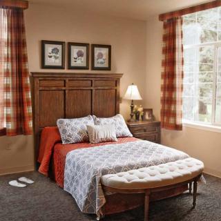 Cozy bedroom with a neatly made bed, wooden furniture, and warm lighting.