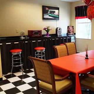 A retro-style kitchen with black and white checkered flooring, red accents, and diner-inspired decor.