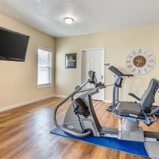 A well-equipped home gym with a stationary bike, treadmill, and mounted television.