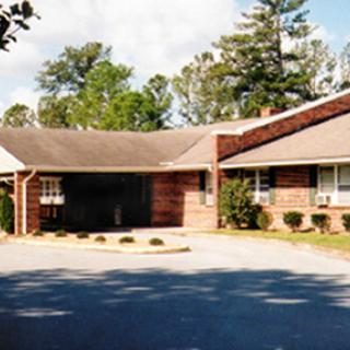 A cozy residential building surrounded by trees and a well-maintained front yard.