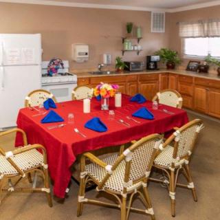 A cozy kitchen and dining area featuring a table with a red tablecloth, blue napkins, flowers, and candles.
