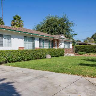 A suburban house with a well-maintained lawn and driveway under a clear blue sky.